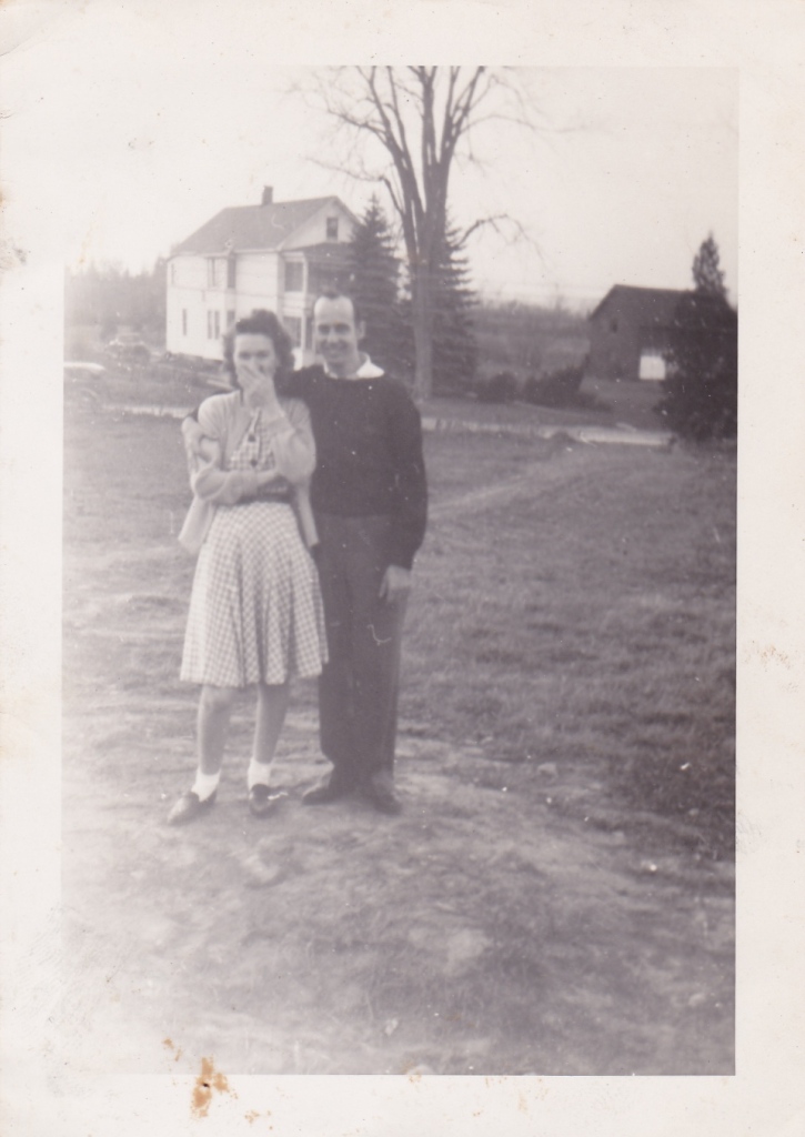 Old photograph of young couple standing close in a yard.