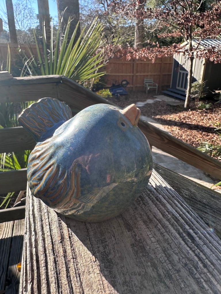 Ceramic fat bluebird with patina of gold mostly on wings and tail. Beak is slightly ajar and pointed upward as if in greeting.