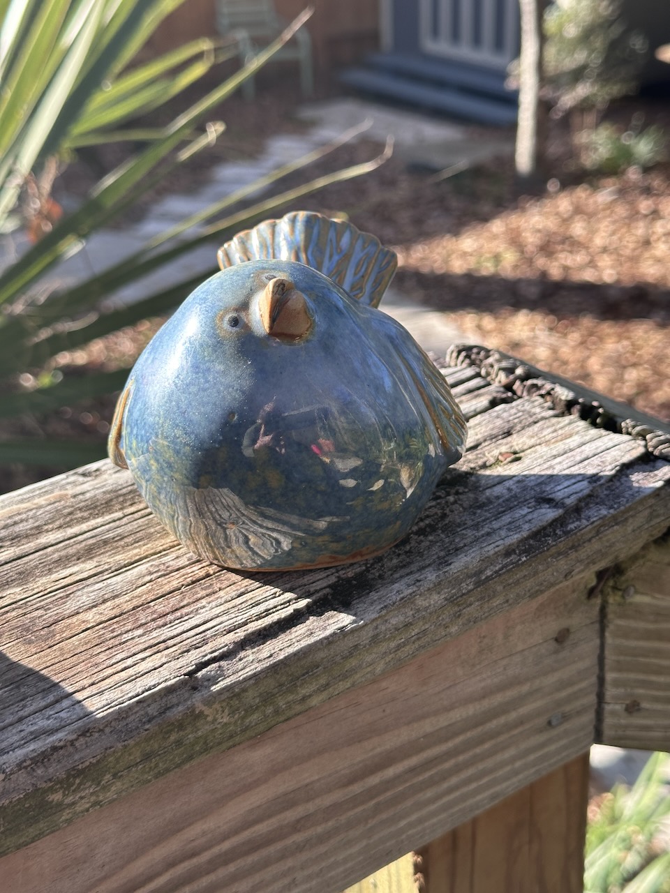 Ceramic fat bluebird with patina of gold mostly on wings and tail. Beak is slightly ajar and pointed upward as if in greeting.